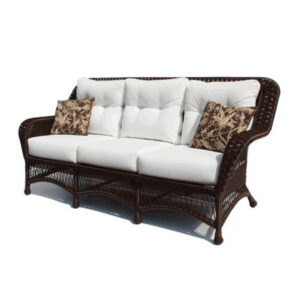 Wicker loveseat with white cushions and patterned throw pillows.