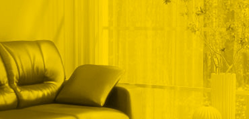 Modern yellow-themed living room corner with sofa and cushion.