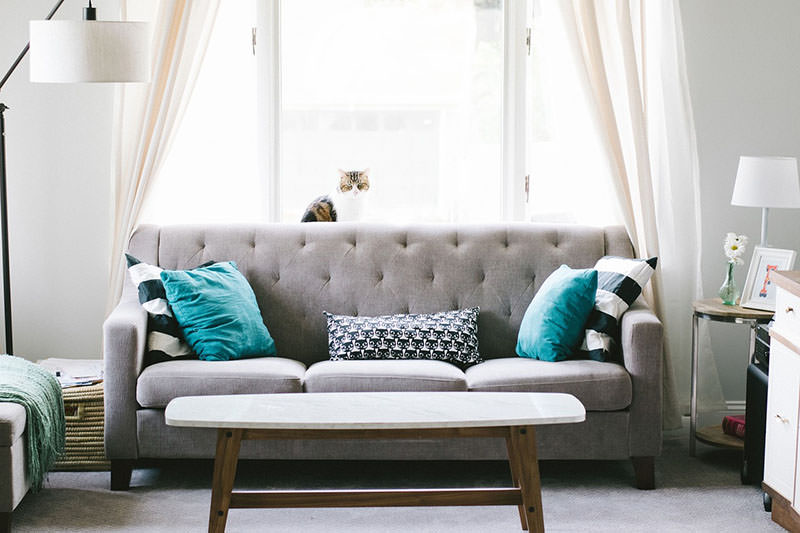 Modern gray sofa with teal and patterned cushions in a bright living room.