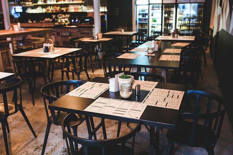Cozy cafe interior with wooden tables and chairs arranged neatly.
