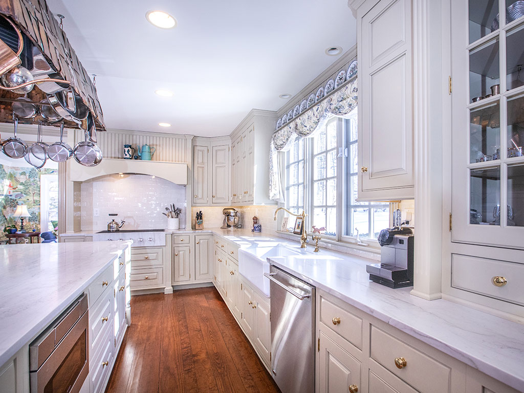 Bright, spacious kitchen with white cabinets and wooden floors.