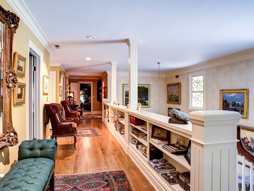 Elegant hallway with wooden floors, built-in shelves, and classic furniture.