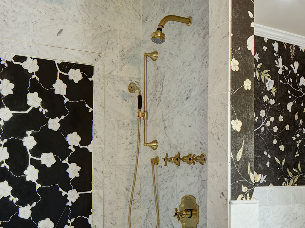 Elegant gold bathroom fixtures with marble walls and patterned tiles.