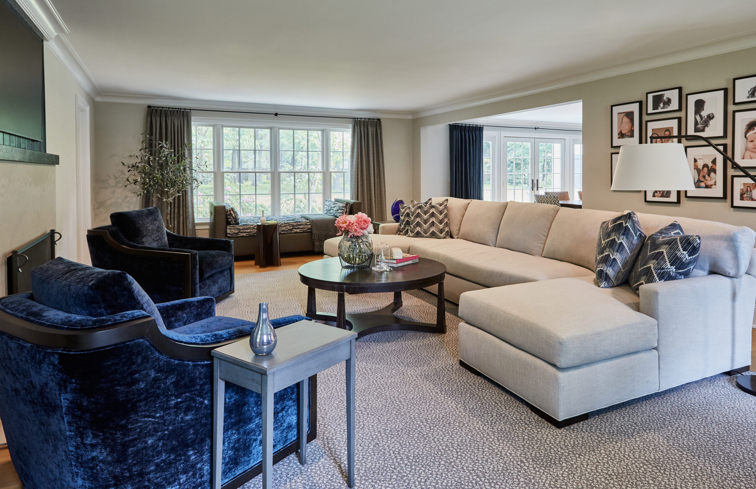 Elegant living room with beige sectional sofa and navy velvet chairs.