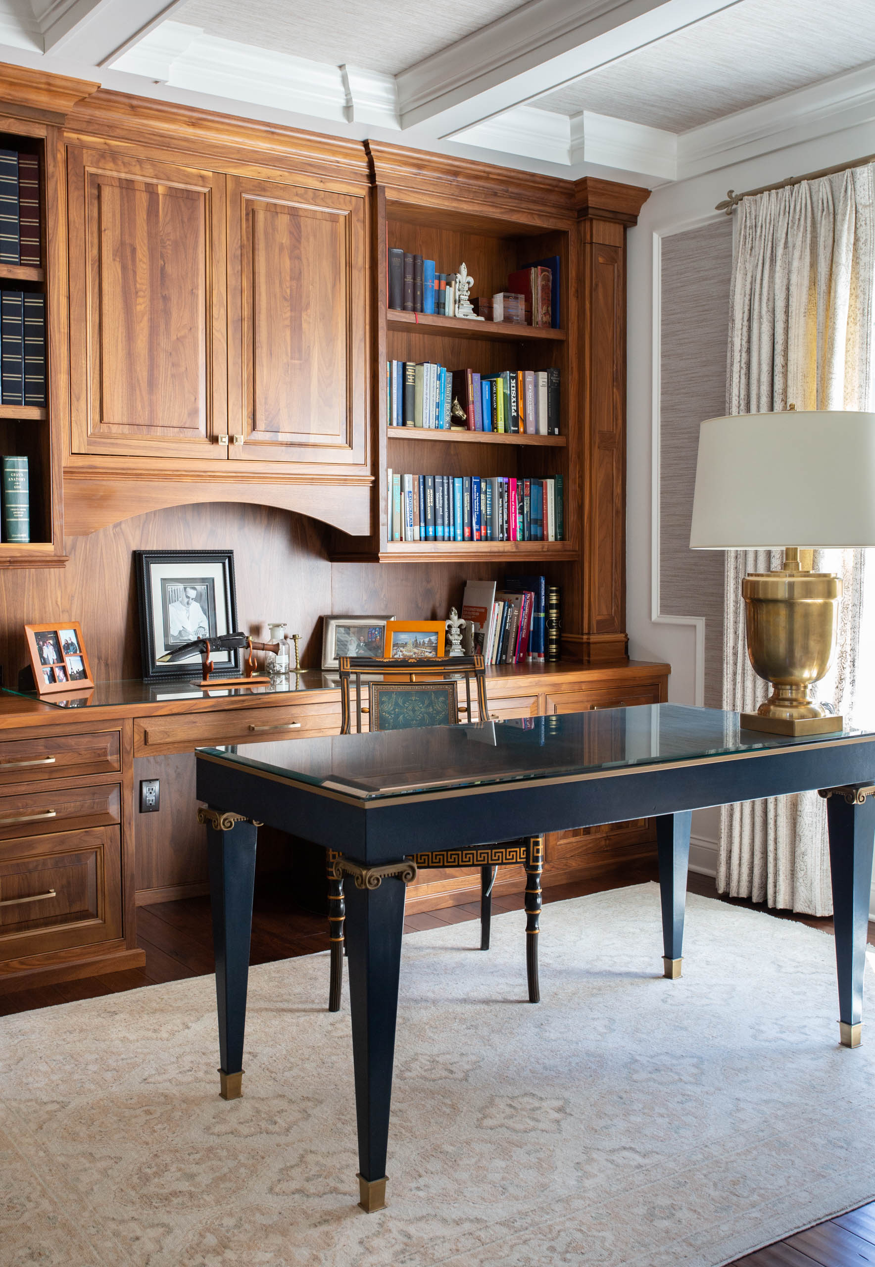 Elegant home office with wooden bookshelves and a black writing desk.